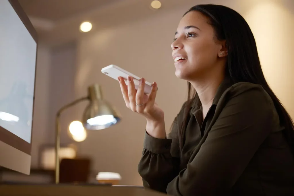 Mulher usando assistente virtual no escritório representa busca por voz no Google