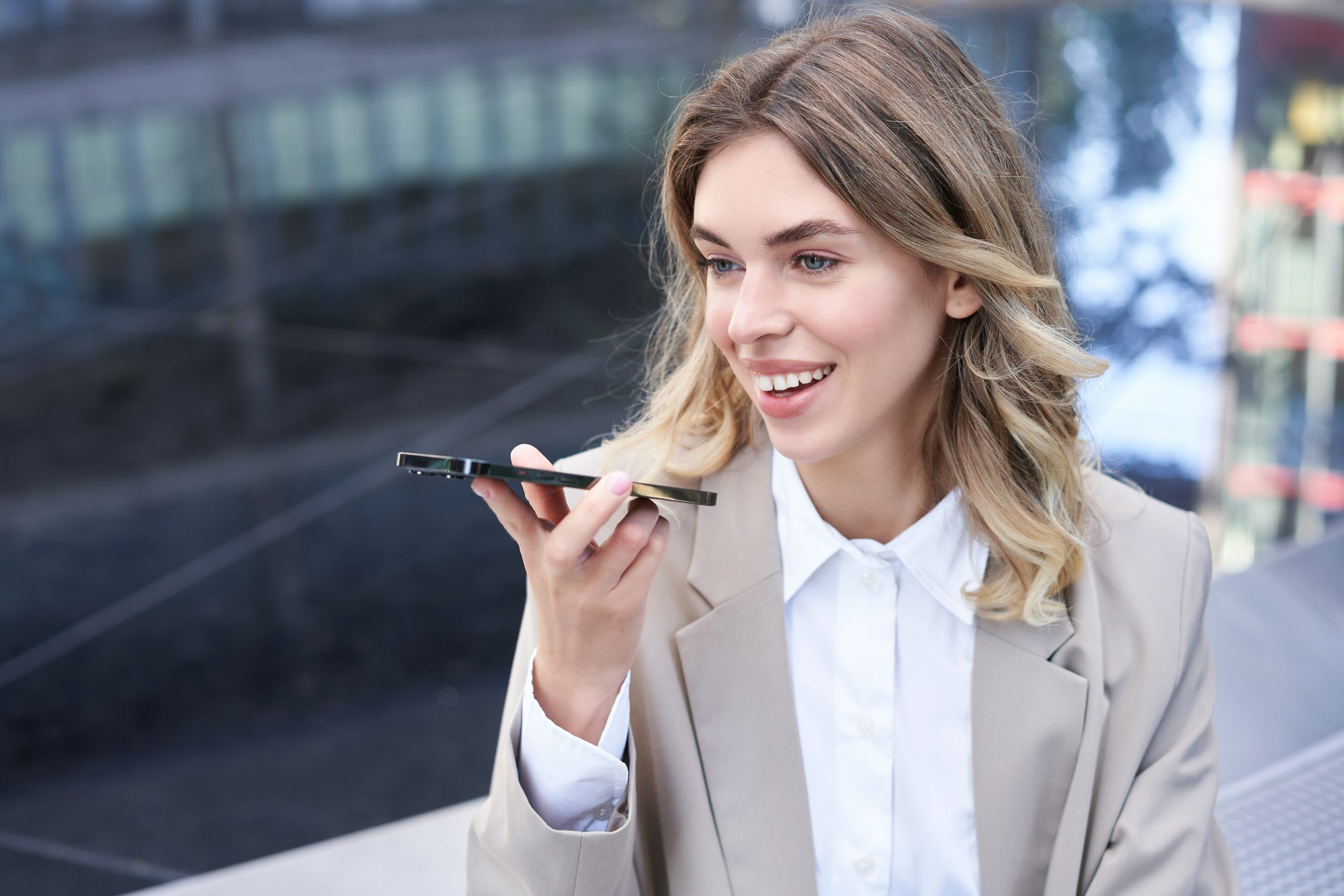 Mulher utiliza pesquisa por voz no celular em ambiente urbano